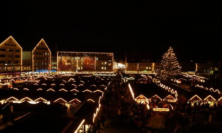 Weihnachtsmarkt von oben mit hellen Lichtern im Dunkeln