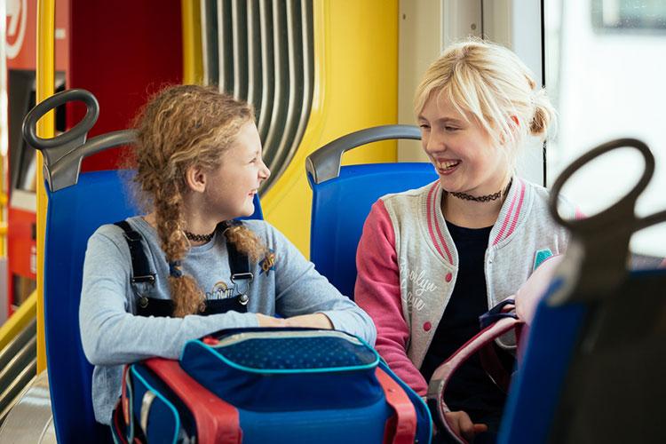 Zwei junge Mädchen mit Schulranzen in der Straßenbahn